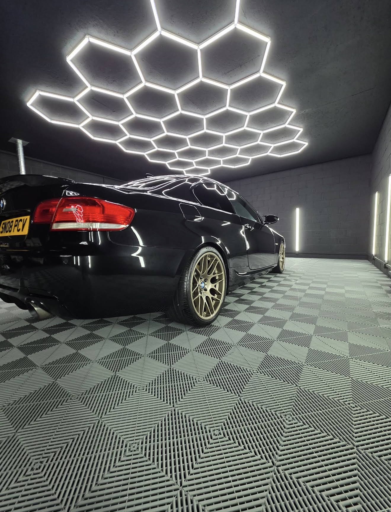 Detailed black BMW coupe under hexagon studio lighting