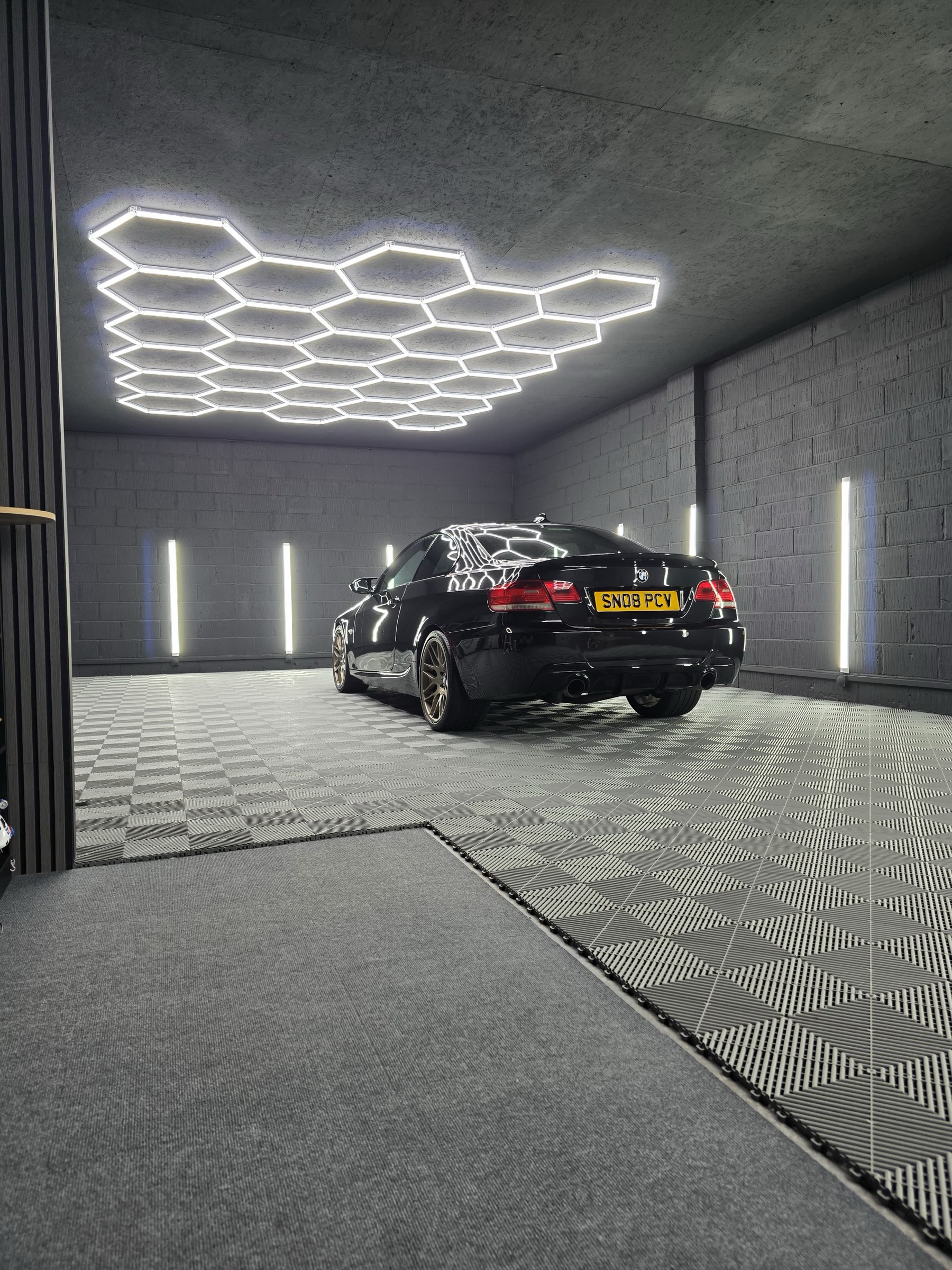 A freshly detailed black BMW glowing under M&M Detailing's hexagon studio lighting